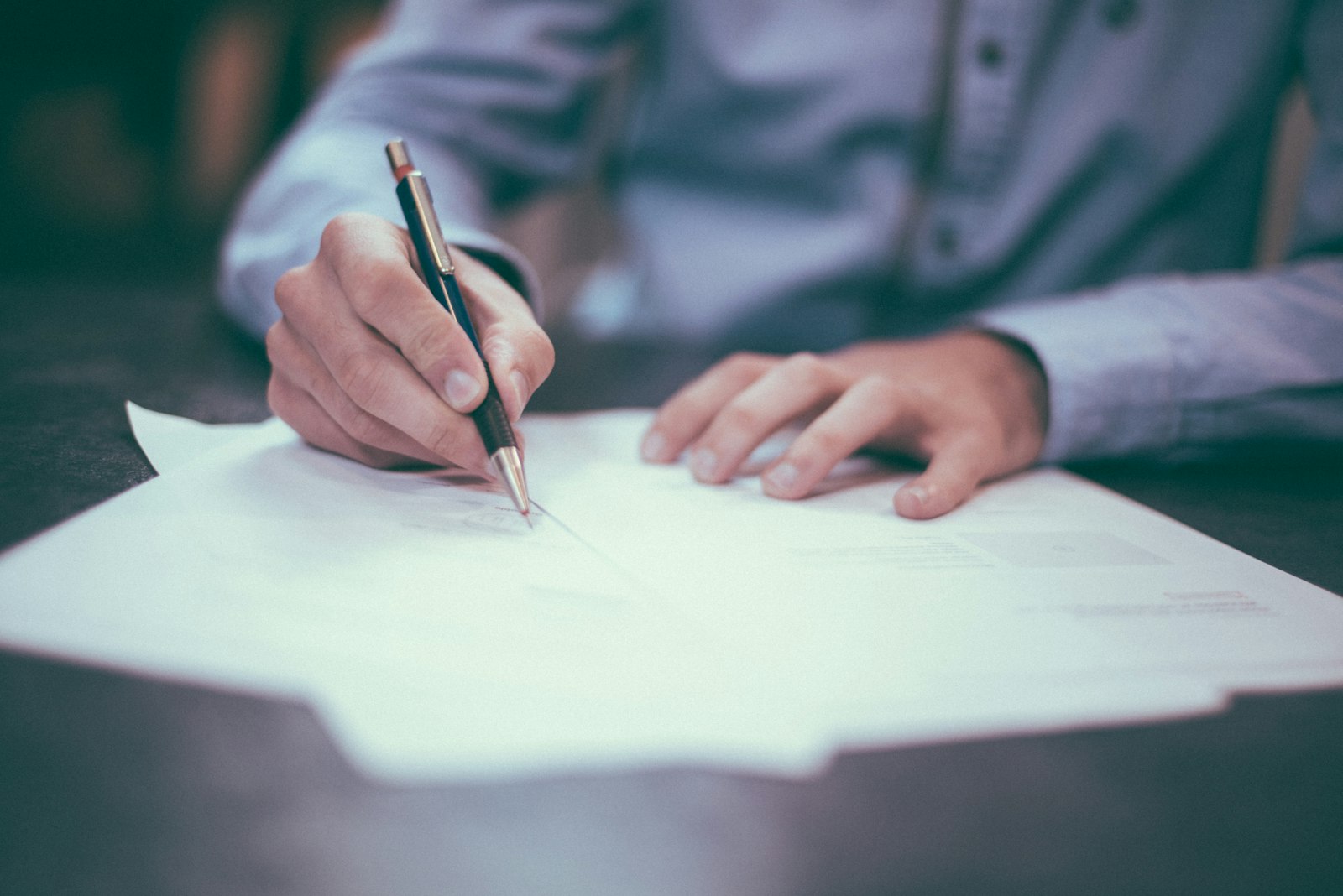 Hands signing a contract — an assurance touchpoint